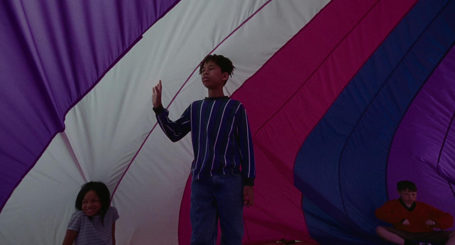 young Owen under gym parachute in trans flag colors